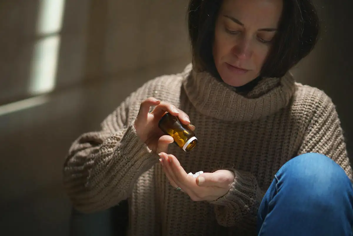 A woman holds a bottle of opioid struggles with opioid addiction