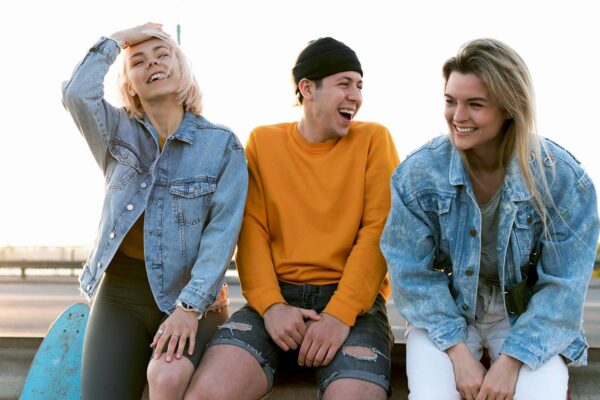 Three young people seated on a bench, laughing together, symbolizing the joy found in drug and alcohol recovery.