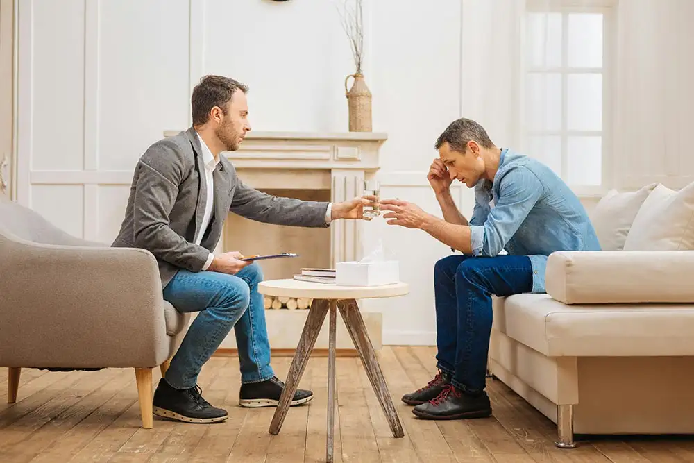 Two men seated on a couch in a living room during opioid addiction treatment