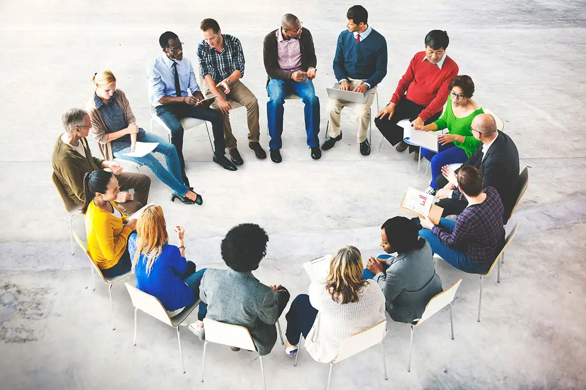 A diverse group of individuals seated in a circle, engaging in a supportive discussion on addiction recovery, group therapy concept