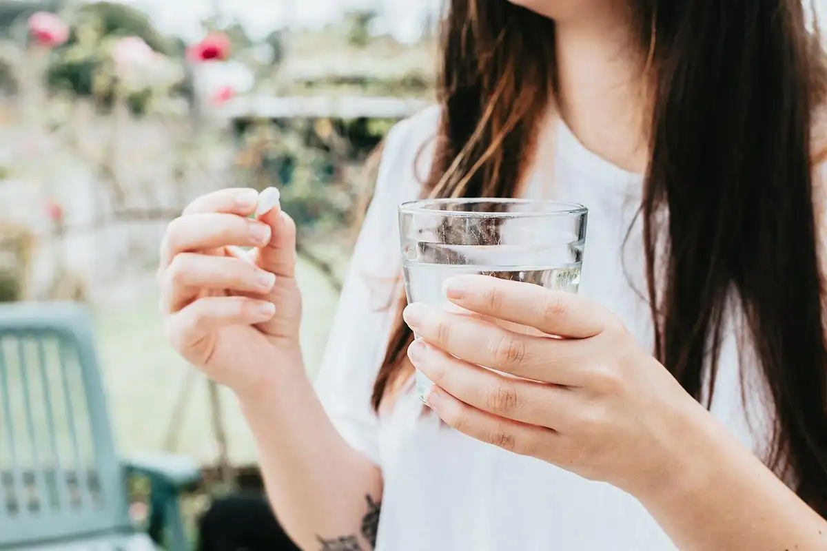 A young woman with a medicine on her palm, highlighting the theme of self-medication and its role in individual health choices