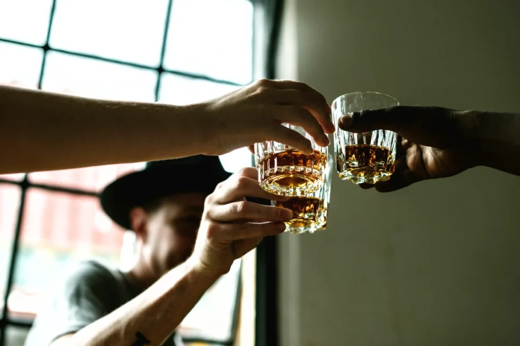 Three people clinking whiskey glasses together, symbolizing a toast to health and good times shared among friends