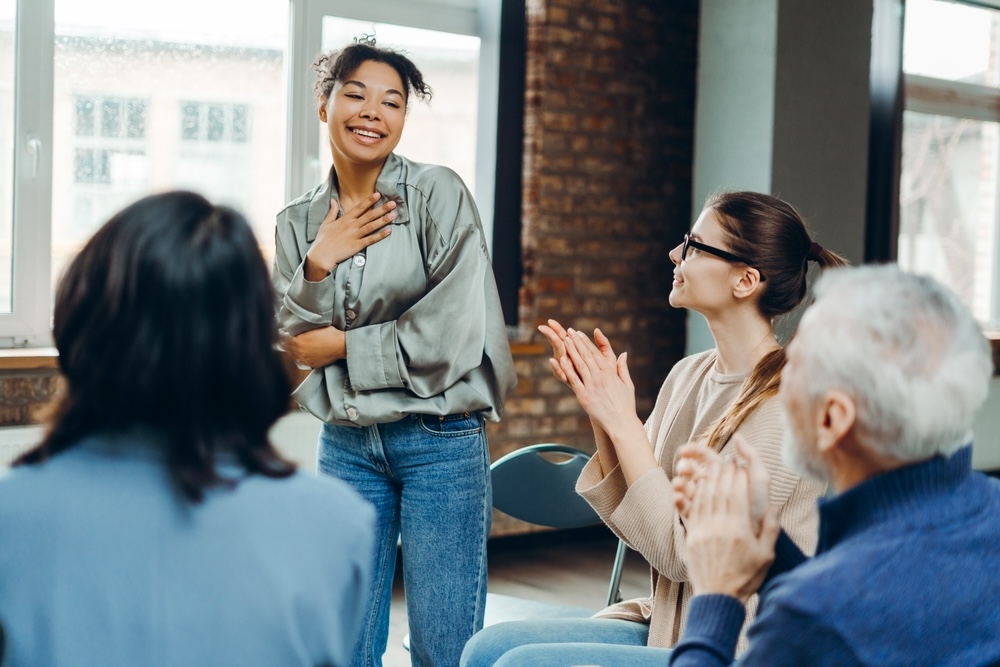 Female standing and smiling during a group therapy session in Menifee luxury drug rehab