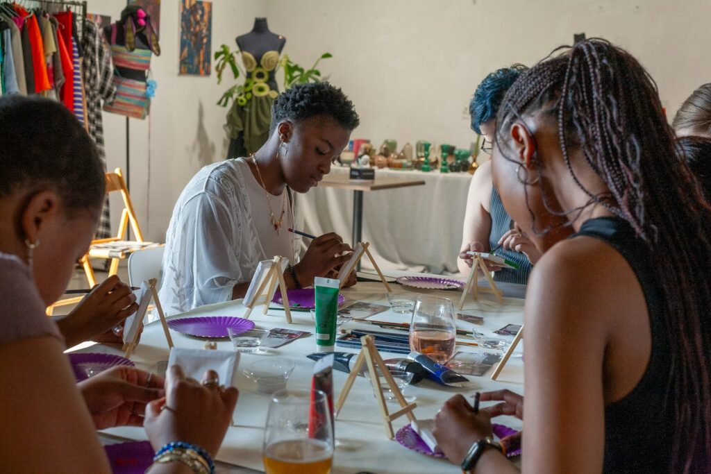 Adults painting together at a table during an art therapy group in addiction treatment